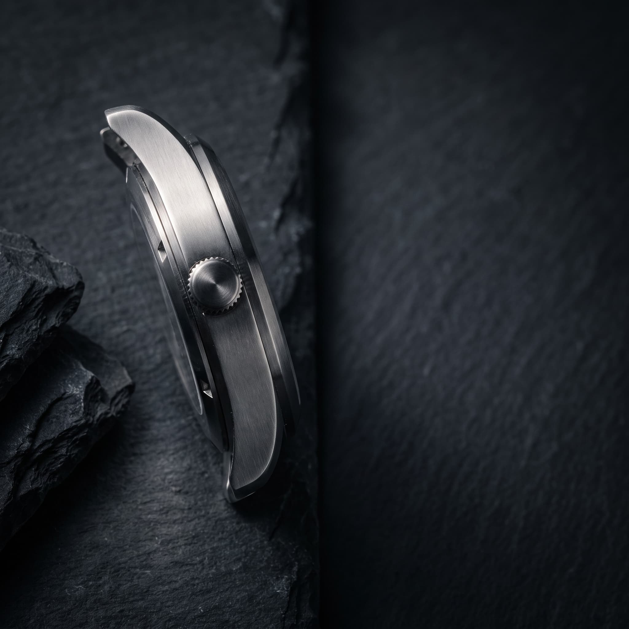 Close frame on an unbranded steel watch case with empty dark space to the right