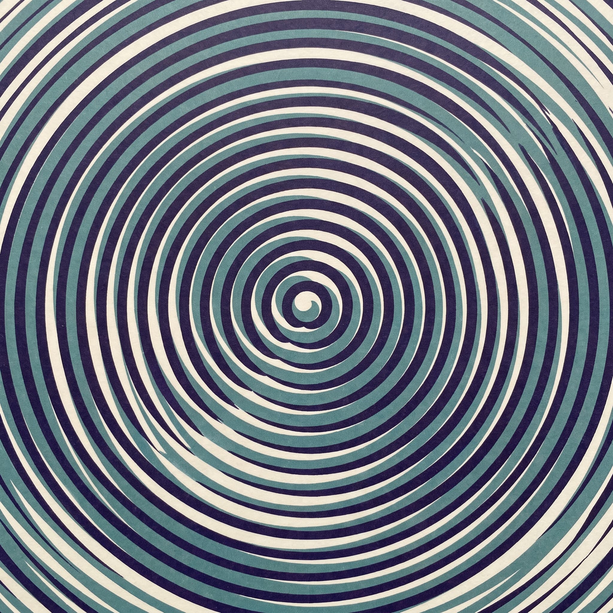 A concentric ring pattern in teal and indigo that appears to drift while static